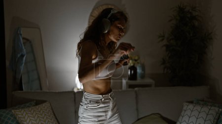 Foto de Una joven escucha música con auriculares en una acogedora sala de estar, disfrutando del tiempo libre en el interior. - Imagen libre de derechos