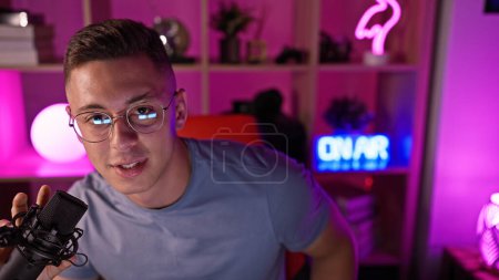 Photo for Hispanic man with microphone in a neon-lit gaming room at night - Royalty Free Image