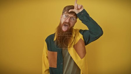 Téléchargez les photos : Rousse ludique barbu homme faire geste drôle isolé sur fond jaune vif - en image libre de droit