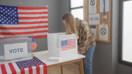 Una joven mujer votando en un centro electoral de EE.UU. con una bandera americana en el fondo.