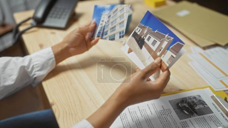 Téléchargez les photos : Une femme examine des photos de bâtiments dans le cadre d'une enquête intérieure, suggérant un accent sur l'analyse immobilière ou le travail de détective. - en image libre de droit