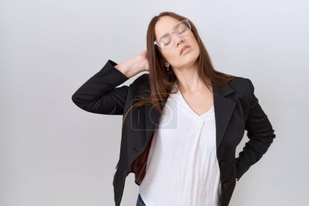 Téléchargez les photos : Belle femme brune portant une veste d'affaires et des lunettes souffrant de douleurs au cou, toucher le cou avec la main, douleurs musculaires - en image libre de droit