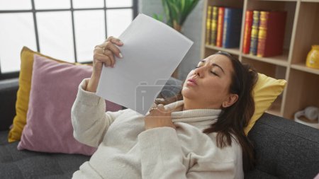 Foto de Mujer hispana leyendo papel en sala de estar con estante - Imagen libre de derechos
