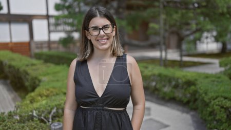 Photo for Joyful and confident, a beautiful hispanic woman in glasses stands by the serene ginkaku-ji temple, her cheerful smile embracing the beauty of kyoto's zen garden - Royalty Free Image