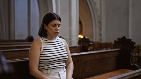 Junge schöne hispanische Frau sitzt auf einer Kirchenbank in der Augustinerkirche in Wien