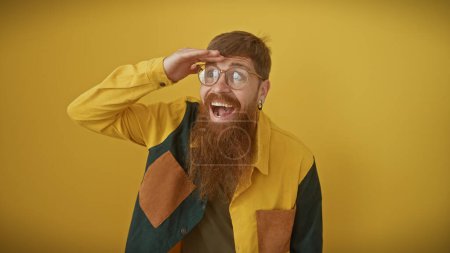 Téléchargez les photos : Un homme roux joyeux avec une barbe saluant sur un fond jaune, exsudant hipster, vibes gaies. - en image libre de droit