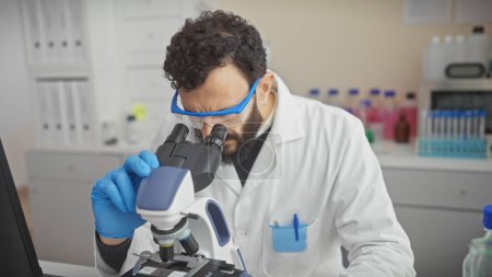 Foto de Hombre científico barbudo utiliza microscopio en investigación de laboratorio. - Imagen libre de derechos