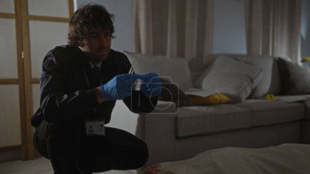Foto de Un detective hispano masculino analiza evidencia en el interior de una escena del crimen, apareciendo enfocado y profesional. - Imagen libre de derechos