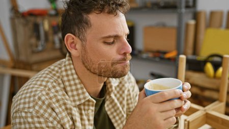 Photo for Hispanic man drinks coffee during a break in a woodworking workshop - Royalty Free Image