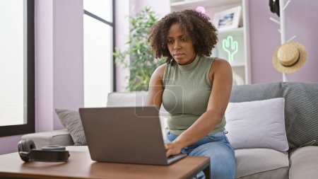 Téléchargez les photos : Femme afro-américaine travaillant sur ordinateur portable à la maison - en image libre de droit