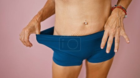 Photo for Close-up view of a woman's toned stomach against a smooth pink background. - Royalty Free Image