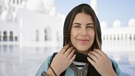 Téléchargez les photos : Une belle jeune femme hispanique adulte posant dans une grande mosquée à abu dhabi, reflétant l'architecture et la culture islamiques. - en image libre de droit
