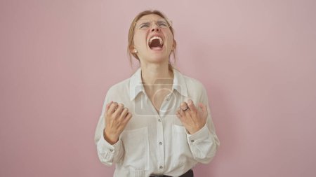 Young caucasian woman in a white shirt yelling with a frustrated expression against a pink background