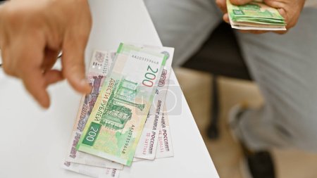 Un primer plano de una mano dando moneda de rublos rusos en una oficina para significar una transacción financiera o soborno.