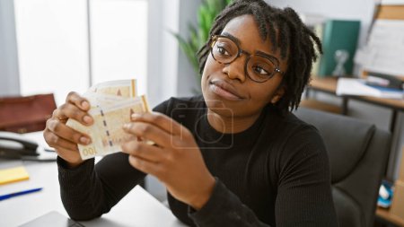 Téléchargez les photos : Une jeune femme afro-américaine examine les billets danois dans un cadre de bureau, dépeignant un thème financier. - en image libre de droit