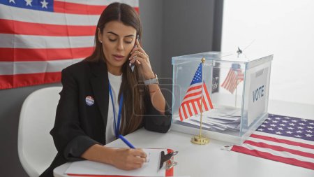 Foto de Mujer hispana habla por teléfono y toma notas en colegio electoral americano con bandera - Imagen libre de derechos