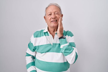 Téléchargez les photos : Homme âgé avec les cheveux gris debout sur fond blanc touchant la bouche avec la main avec une expression douloureuse en raison de maux de dents ou de maladies dentaires sur les dents. dentiste - en image libre de droit