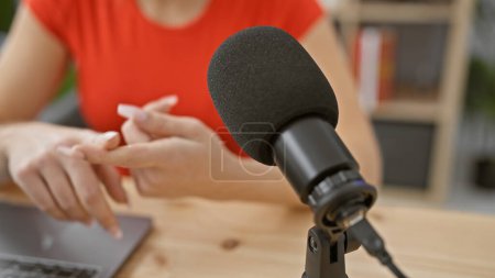 Téléchargez les photos : Une jeune femme caucasienne aux cheveux blonds parlant dans un studio de radio, représentée du point de vue du microphone. - en image libre de droit