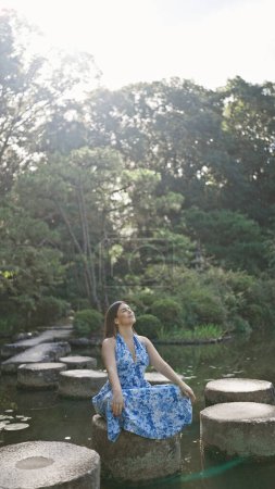 Hermosa mujer hispana meditando en el camino de piedra en el lago Heian Jingu, abrazando el zen de la naturaleza en el verano kyoto