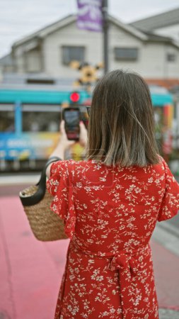 Stunning hispanic woman in glasses capturing tokyo train journey on her smart phone - an exciting mixture of modern lifestyle, urban architecture and cityscape tourism