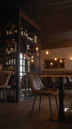 Elegantes Restaurant-Interieur mit Weinflaschen und Lederstühlen, das Speisen, Luxus und warmes Ambiente darstellt.