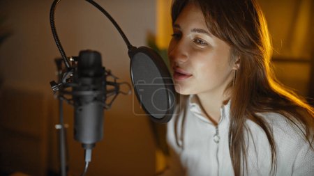Foto de Una joven mujer caucásica graba voces en un estudio de música, exudando talento y dedicación. - Imagen libre de derechos