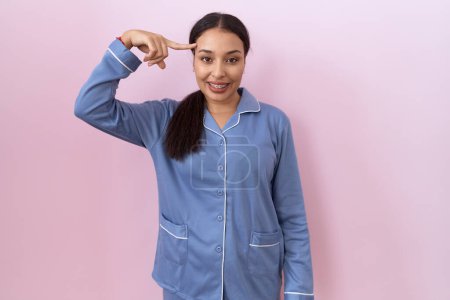 Photo for Young arab woman wearing blue pajama smiling pointing to head with one finger, great idea or thought, good memory - Royalty Free Image
