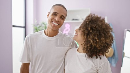 Photo for Confident, beautiful couple hugging and smiling in their cozy home, embracing their love and happiness together - Royalty Free Image