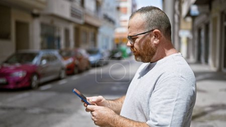 Caucasian man using smartphone with serious expression at street