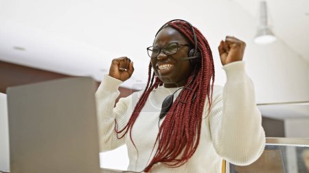 Téléchargez les photos : Femme afro-américaine avec des tresses célèbre le succès dans un cadre de bureau, illustrant les réalisations sur le lieu de travail. - en image libre de droit