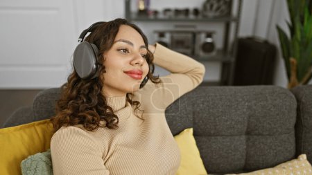 Téléchargez les photos : Relaxed woman enjoying music with headphones in a cozy living room interior - en image libre de droit
