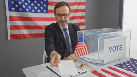 Reifer bärtiger Mann im Anzug wirft Stimmzettel in Wahlurne, Fahnen zieren Wahllokal.