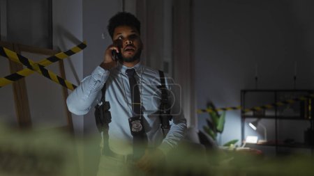 Foto de Detective afroamericano en una estación de policía haciendo una llamada telefónica, rodeado de tenue iluminación y cinta de precaución. - Imagen libre de derechos