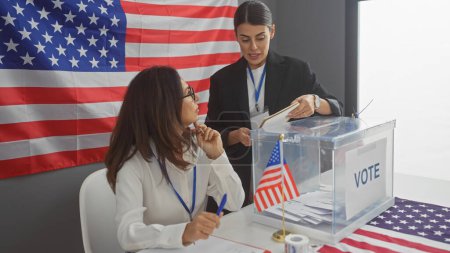 Téléchargez les photos : Deux femmes votant à l'intérieur avec drapeau américain et urne - en image libre de droit