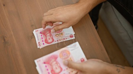 Indoor snapshot, dynamic young man making money count, sitting cozily on sofa at home, banking wealth of yuan banknotes  a peek into chinese economy 