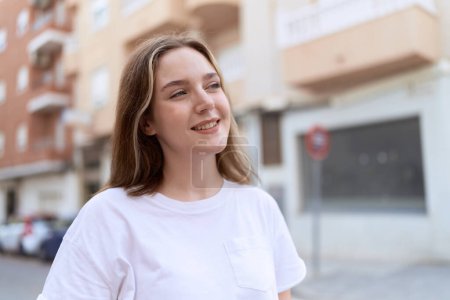 Téléchargez les photos : Jeune femme caucasienne souriant confiant regardant vers le côté à la rue - en image libre de droit