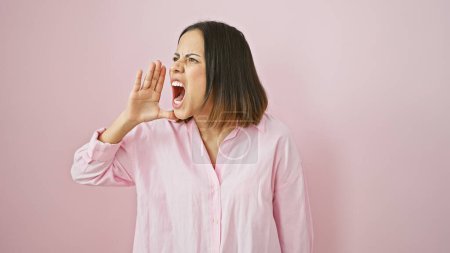 Photo for A young hispanic woman wearing a pink shirt yells against a plain pink background. - Royalty Free Image