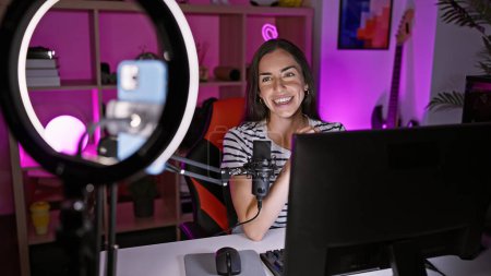 Foto de Joven hermosa mujer hispana streamer sonriendo confiado tener videollamada en la sala de juegos - Imagen libre de derechos