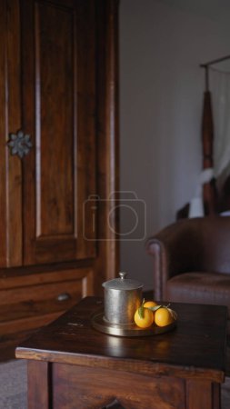 Téléchargez les photos : Une théière vintage en étain et des oranges fraîches sur une table en bois élégamment disposée dans un intérieur confortable et rustique. - en image libre de droit