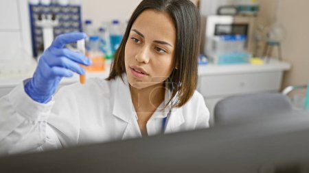 Photo for Hispanic woman scientist analyzing a sample in a laboratory setting, wearing a lab coat and gloves. - Royalty Free Image
