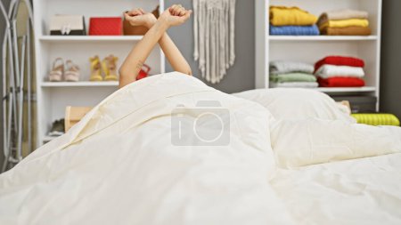 A person stretching in bed amidst a cozy bedroom setting, reflecting a sense of relaxation and comfort.