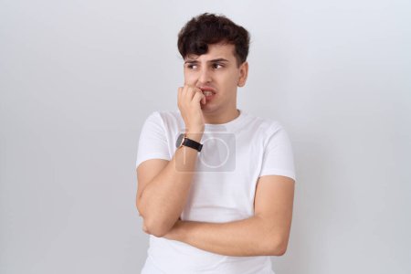Photo for Young non binary man wearing casual white t shirt looking stressed and nervous with hands on mouth biting nails. anxiety problem. - Royalty Free Image
