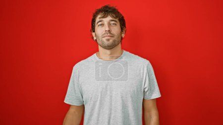 Photo for Young man standing with serious expression over isolated red background - Royalty Free Image