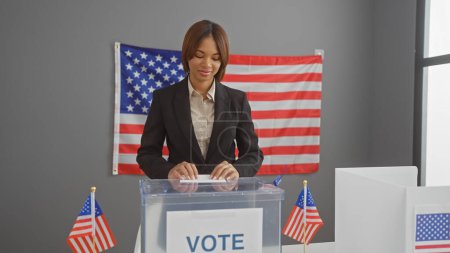 African american woman at voting booth with us flags in electoral college interior.