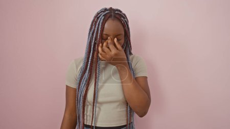 Téléchargez les photos : Portrait d'une femme afro-américaine contemplative avec des tresses sur fond rose, incarnant la beauté et la prévenance. - en image libre de droit