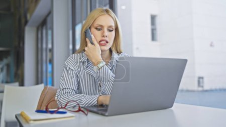 Téléchargez les photos : Une jeune femme blonde multitâches avec un téléphone et un ordinateur portable dans un café urbain extérieur moderne. - en image libre de droit
