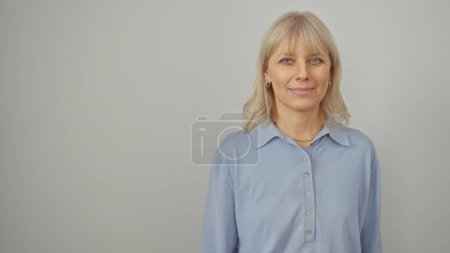 Foto de Un retrato de una mujer rubia sonriente con una camisa azul sobre un fondo blanco, exudando confianza y belleza. - Imagen libre de derechos