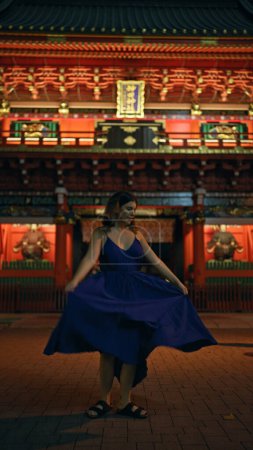 Enchanting night in tokyo, beautiful hispanic woman captured spinning around in a dress at a traditional japanese temple
