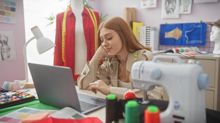 Téléchargez les photos : Une femme réfléchie tailleur avec ordinateur portable et équipement de couture dans un atelier coloré - en image libre de droit