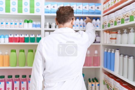 Photo for Middle age man pharmacist holding product on shelving at pharmacy - Royalty Free Image